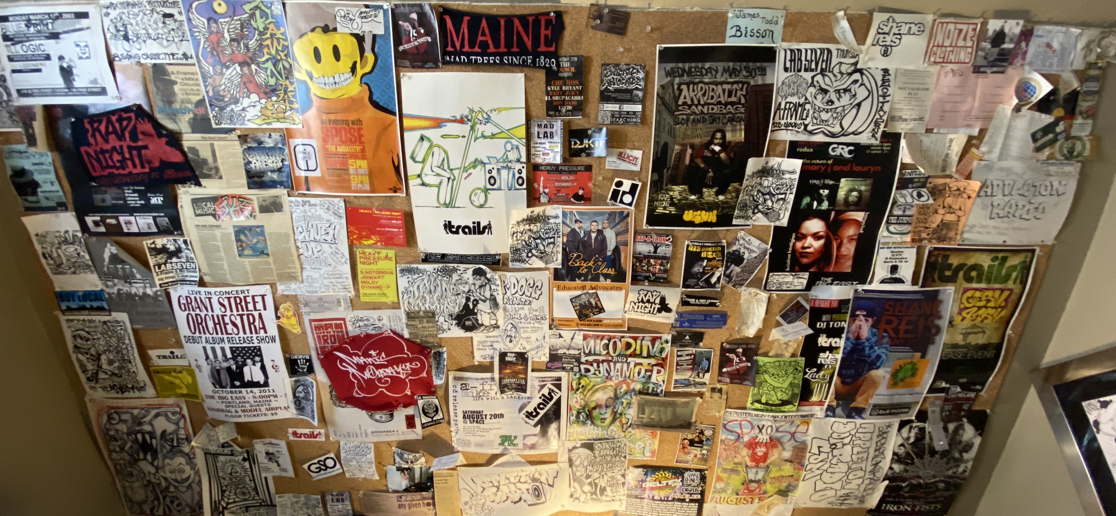 The Appleton Radio studio bulletin board covered with Maine hip-hop flyers, artwork, photographs, stickers, and memorabilia